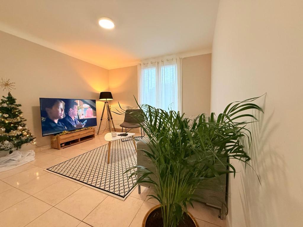 ein Wohnzimmer mit einem TV und einer Topfpflanze in der Unterkunft Beauséjour in Saint-Herblain