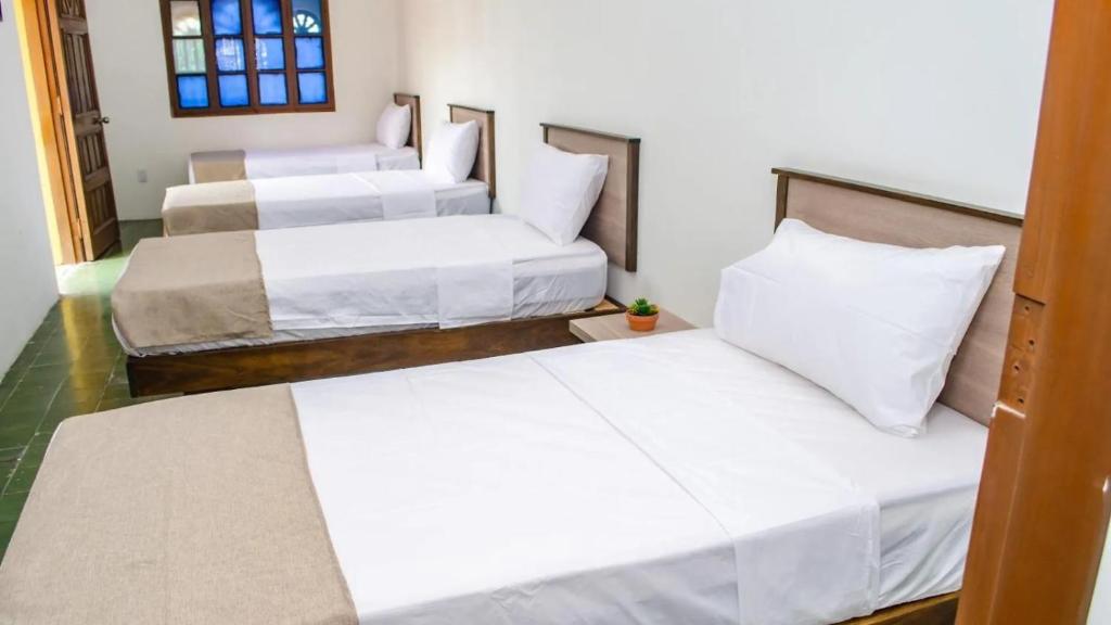 a group of three beds in a room at SGH Hotel San Agustin in Santa Marta