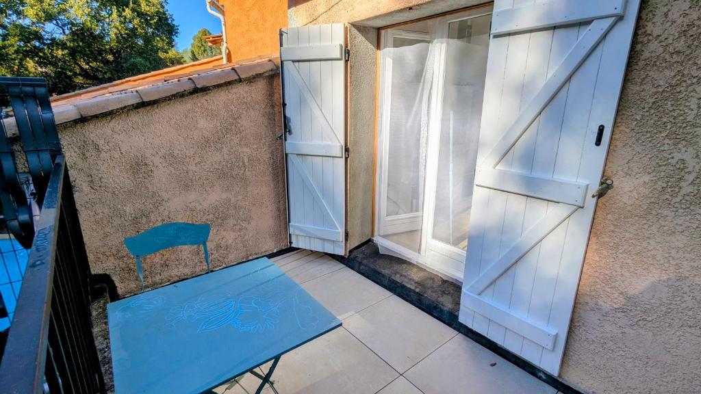 an open door and a blue chair on a balcony at Le Plein Sud - Carqueiranne in Carqueiranne