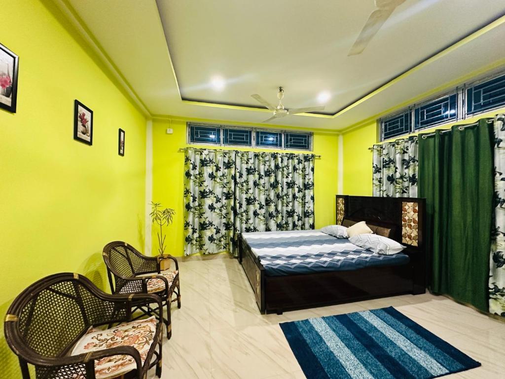 a bedroom with yellow walls and a bed and chairs at KARDOM Homes Moran in Morānha