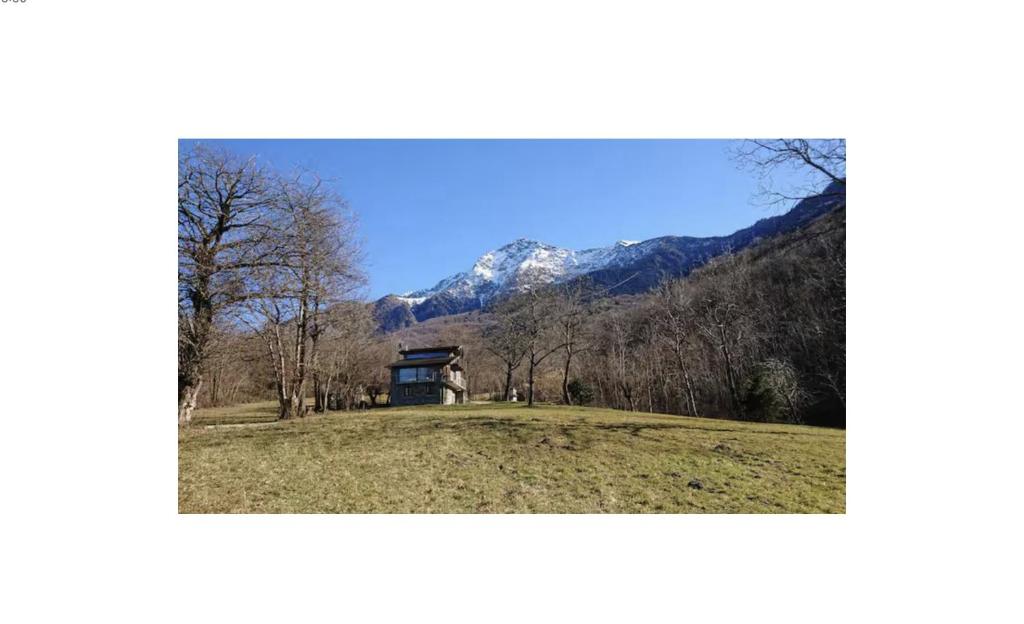una casa en una colina con una montaña al fondo en Rustico Prato Grande con vista lago, en Carriola