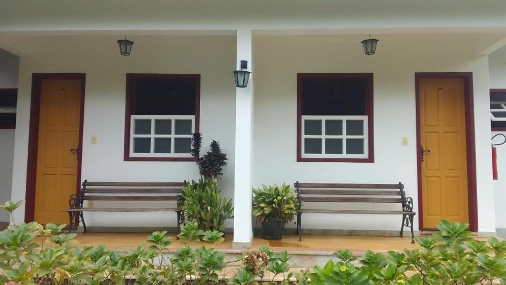 two benches sitting in front of a white building at Pousada da Serrinha in Mariana