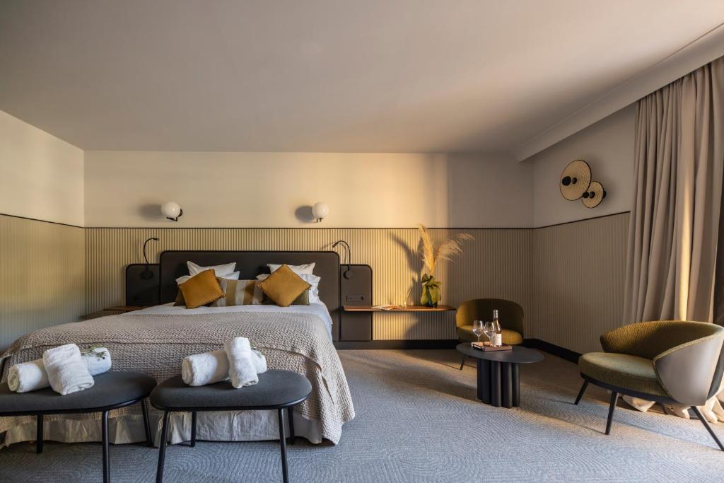 a bedroom with a bed and two chairs at Les Villas du Château de Lastours in Portel-des-Corbières