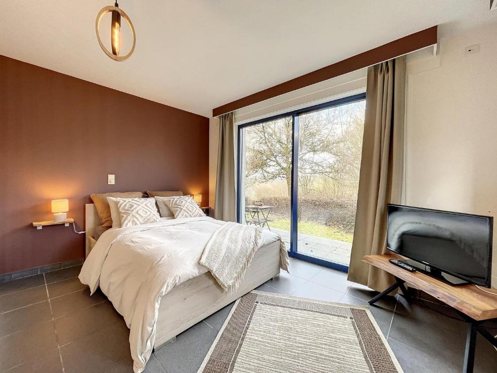 une chambre avec un lit, une télévision et une fenêtre dans l'établissement Au doux Durbuy, à Durbuy