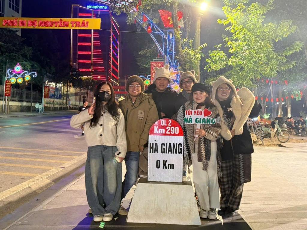 Un grupo de personas de pie junto a un cartel en una calle. en Mùa Pửi Lô lô homestay, en Mèo Vạc