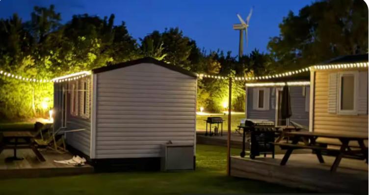a campsite with a picnic table and a tent with lights at Tinyhouse 6 Ferienwohnung Mobilheim Fehmarn in Fehmarn