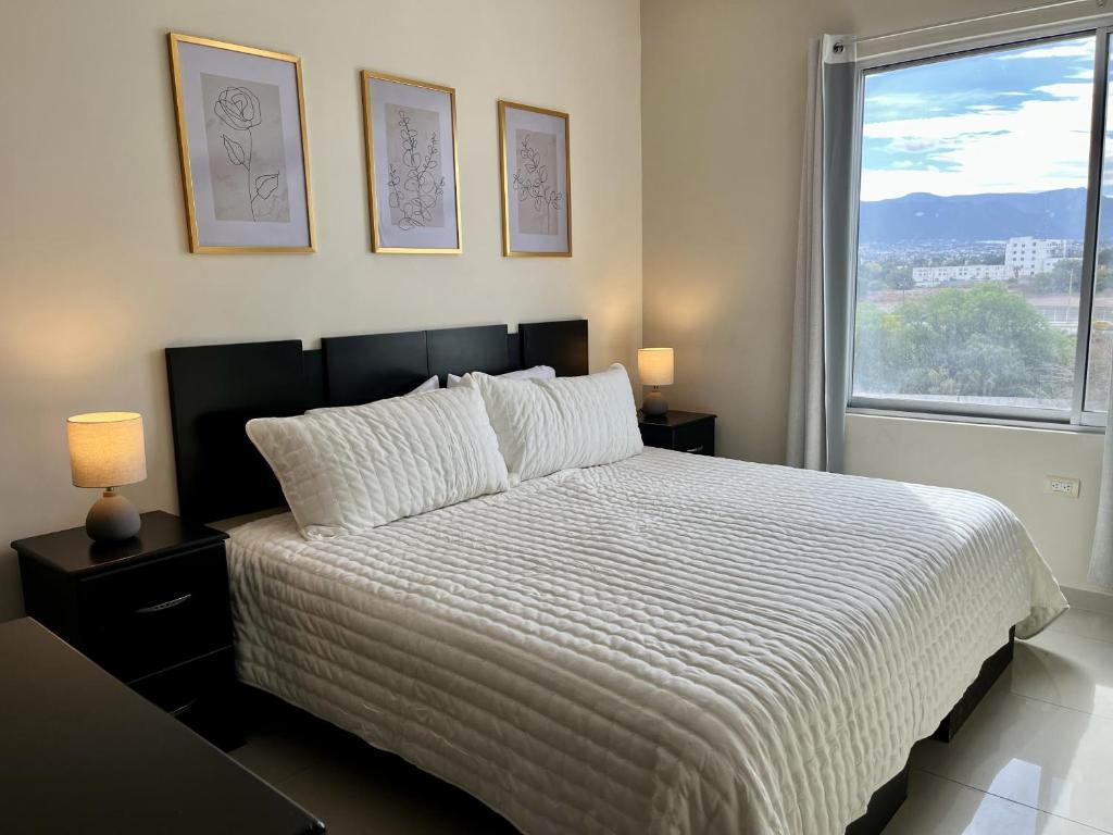 Loft con Luz Natural y Cocina Equipada في سالتيلو: غرفة نوم بسرير لحاف أبيض ونافذة