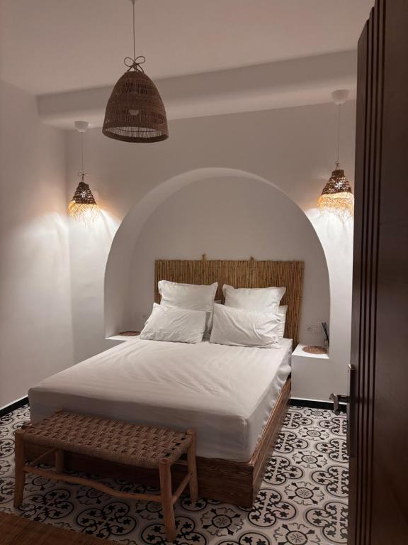 Un dormitorio con una cama blanca con cabecero de madera. en Casa Norte, en Tetuán
