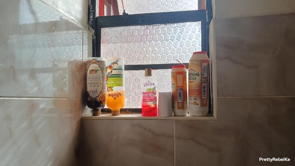 ThikaSunrise apartment next to bullys hotel的淋浴间角落的架子上放着一些瓶子