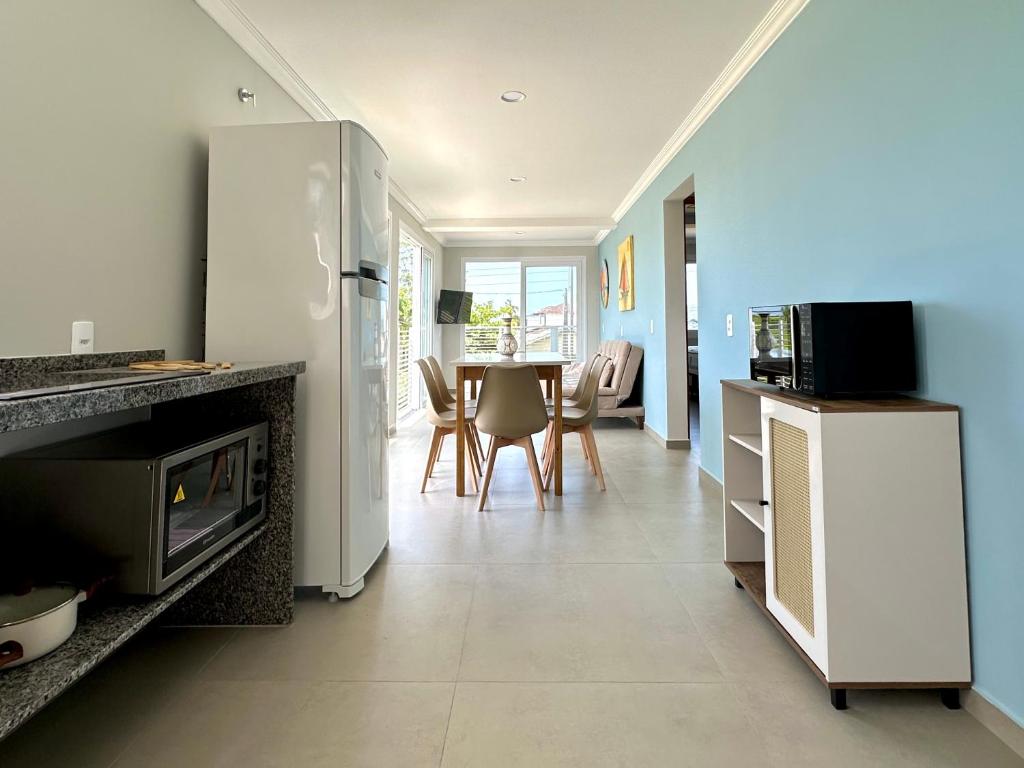 Apê Alegria - Capri Morada & Mar - Frente mar في ساو فرانسيسكو دو سول: مطبخ مع ثلاجة وطاولة مع كراسي