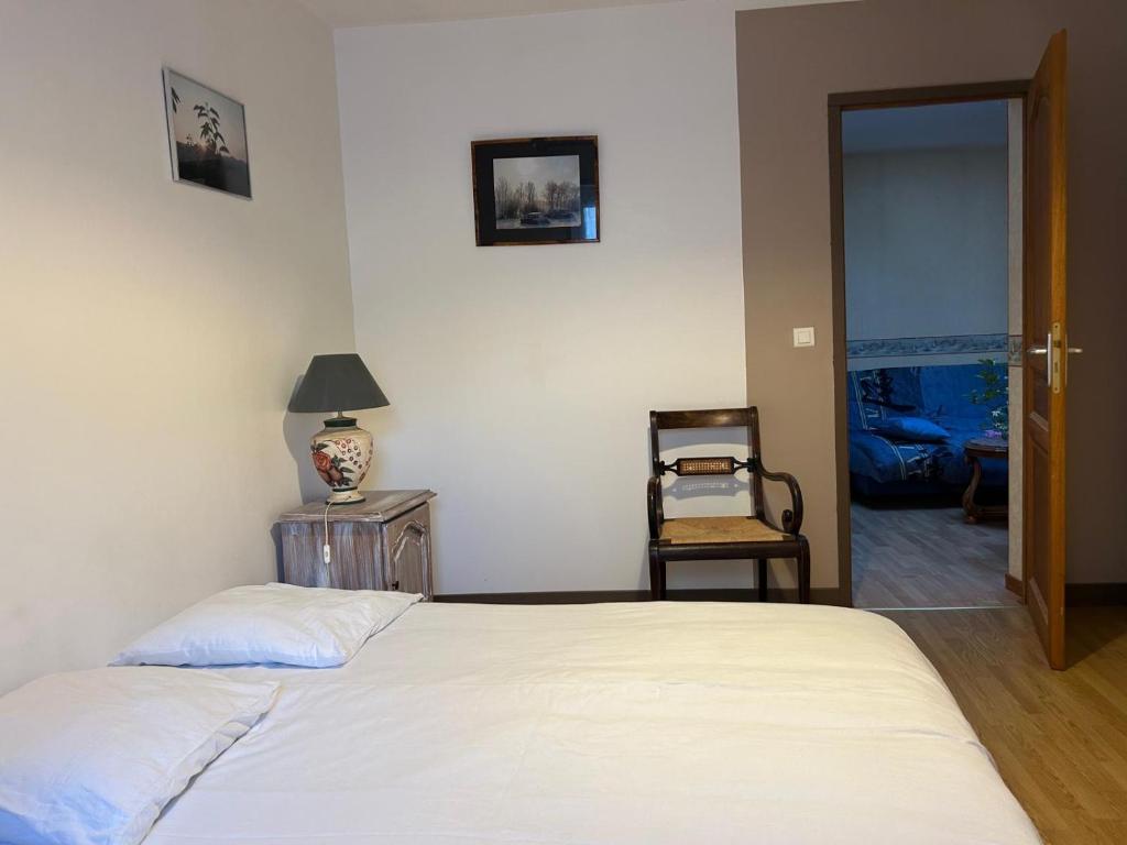 a bedroom with a white bed and a chair at 2 Chambres dans maison typique in Beaumont-lès-Valence