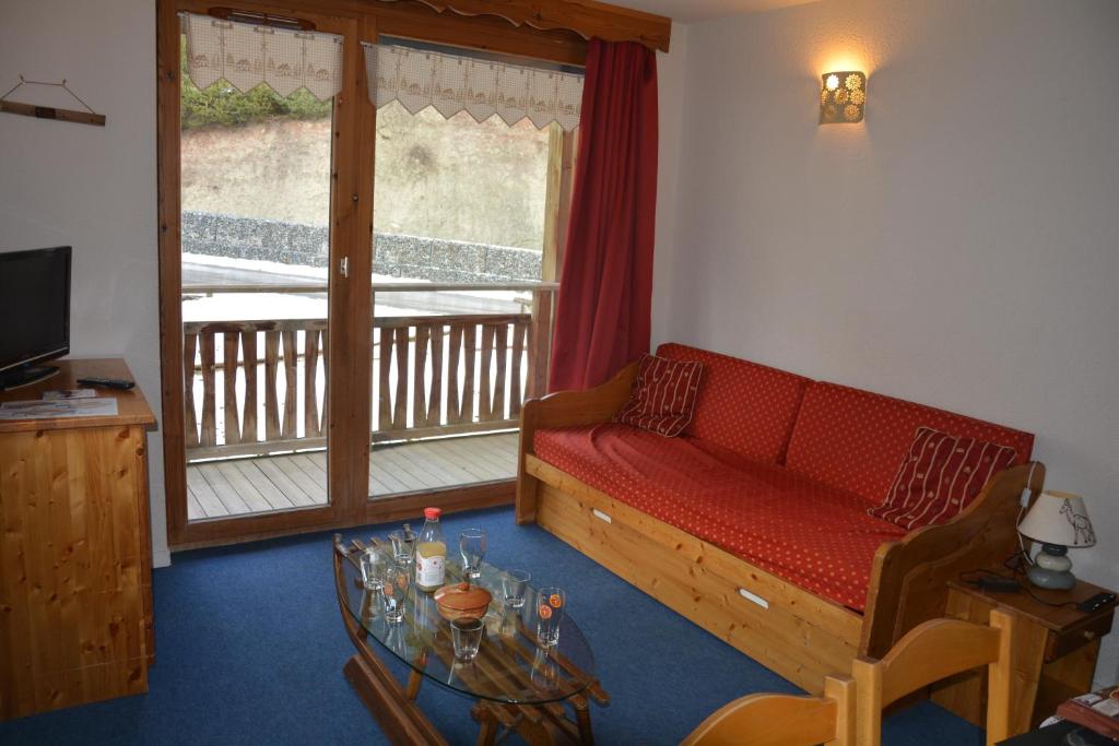 a living room with a red couch and a table at l'Antre du Cerf in Villarodin-Bourget