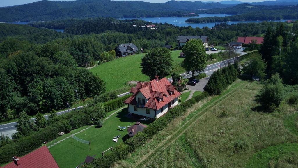 a house with a red roof on a green field at Bieszczady111 in Polańczyk