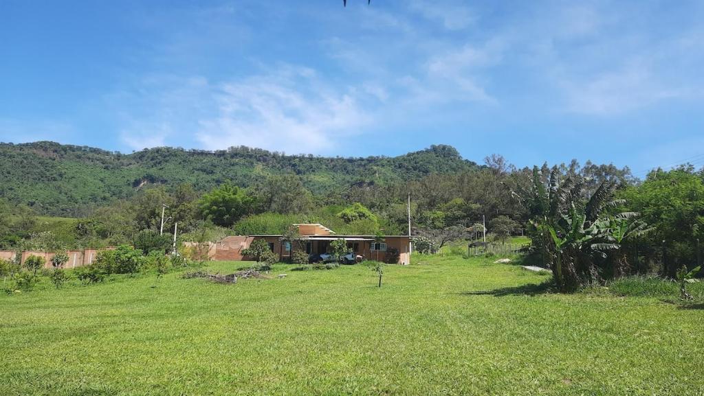 a house in the middle of a field with a hill at Suite na Natureza com Café da Manhã in São Pedro
