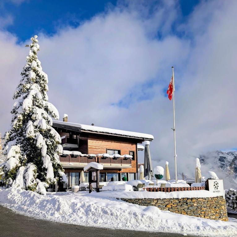a ski lodge with a snow covered tree and a flag at Guesthouse Hotel Between in Chamoson