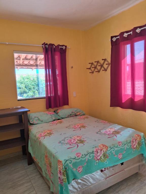 a bedroom with a bed and a window with purple curtains at Pousada dunas in Barroquinha
