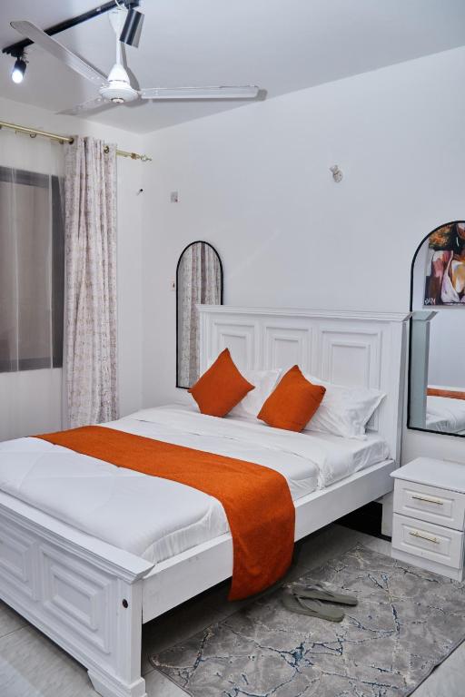a white bed with orange pillows in a bedroom at Darflings Haven-Diani in Ukunda