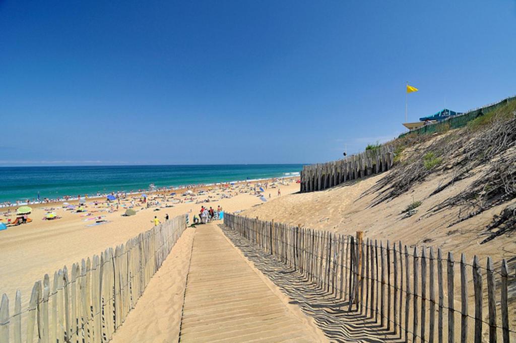 a sandy beach with a wooden boardwalk leading to the ocean at Aux portes de l ocean in Labenne