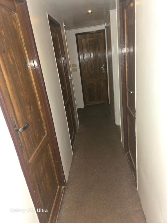 een lege gang met houten deuren en tapijt bij The grand in Nag` el-Ramla