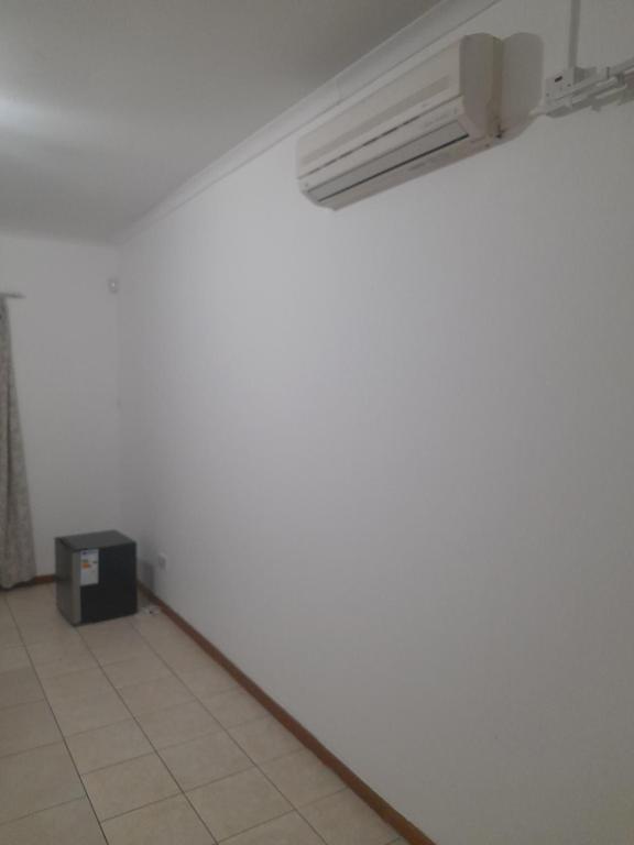 Primestay Homestead في غابورون: غرفة ذات جدار أبيض ومدفأة سوداء