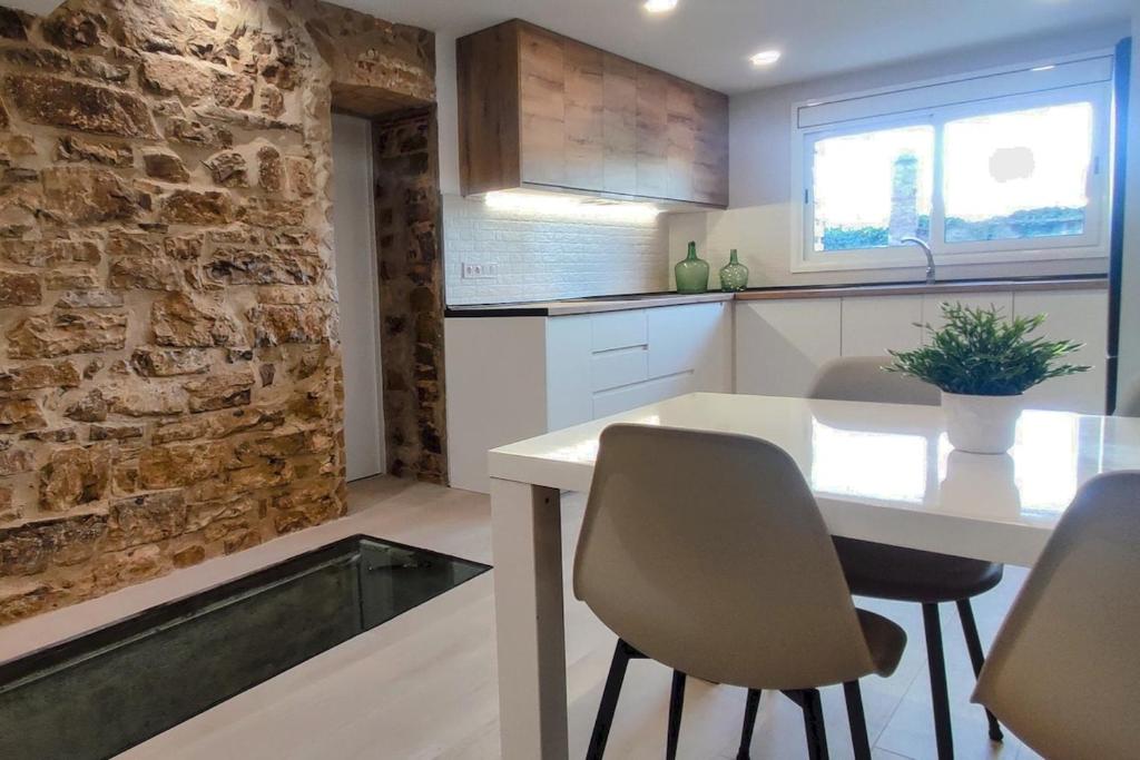 a kitchen with a table and chairs and a stone wall at Casa de poble Cal Casellas in San Martín Sasgayolas
