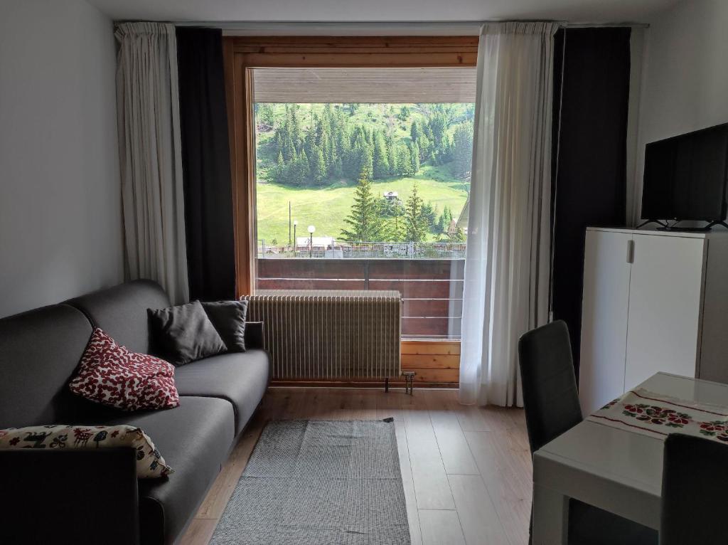 a living room with a couch and a large window at AL18 bilocale in Santa Caterina Valfurva