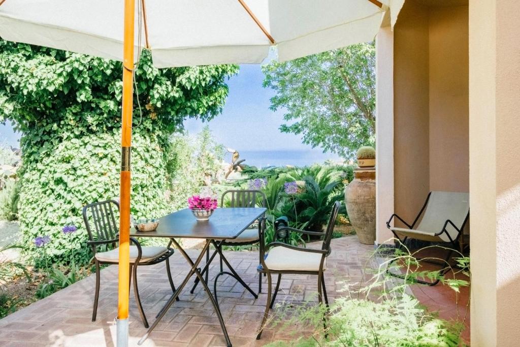 a patio with a table and chairs and an umbrella at Villino Eleonora in Parghelia