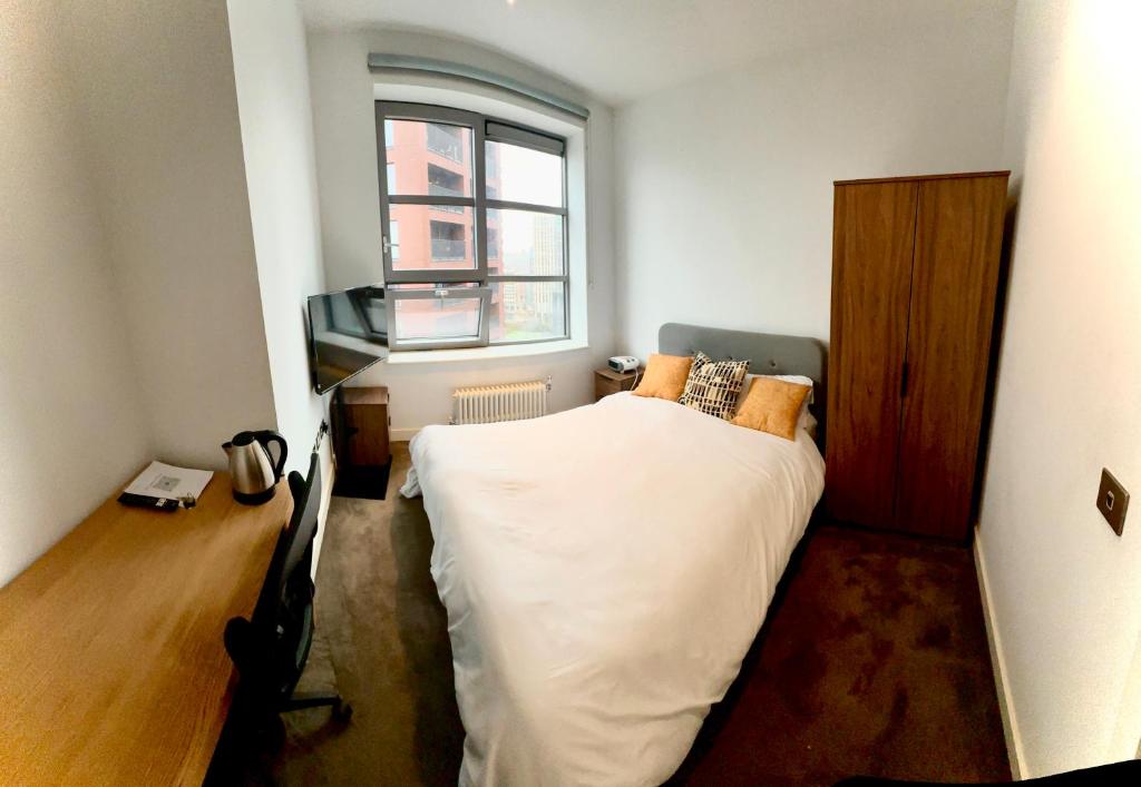 Un dormitorio pequeño con una cama y una ventana. en Luxurious and Spacious Central London room in Canary Wharf with a City View & a Private Bathroom, en Londres