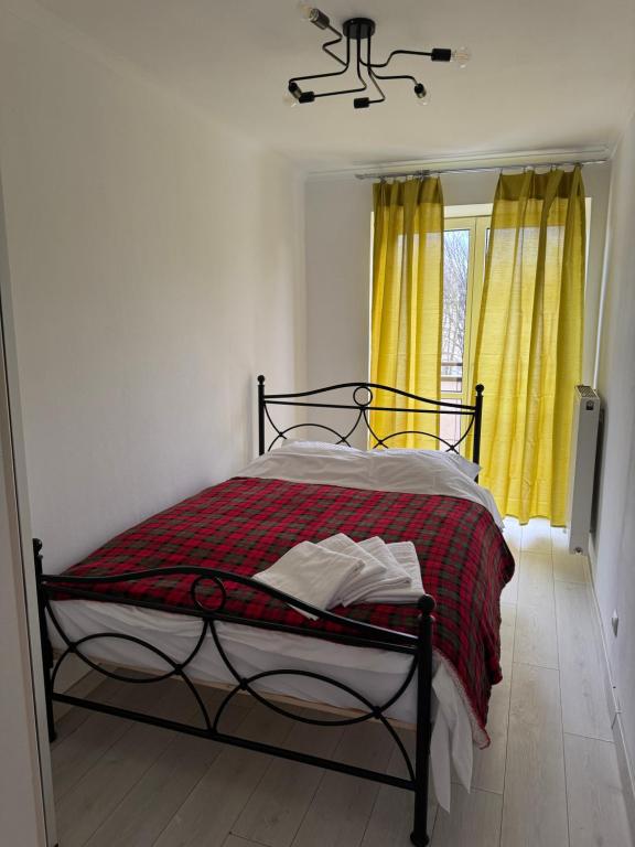 una camera da letto con un letto con una coperta rossa e tende gialle di Przytulny a Bielsko-Biała