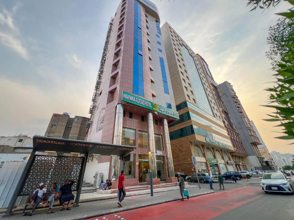 a tall building with people sitting in front of it at فندق مهوى الفؤاد - المعابدة in An Naqāʼ