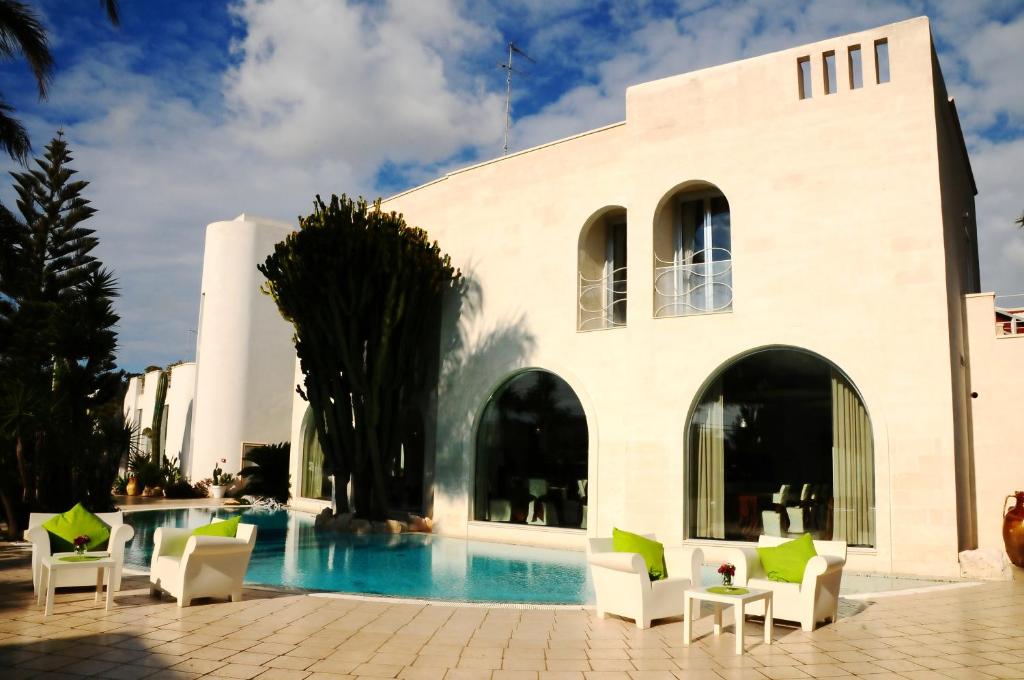 a resort with a swimming pool and chairs and a building at Il Grillo Hotel in Pulsano