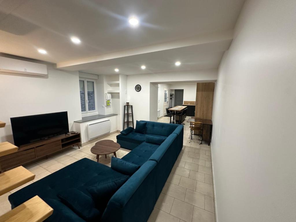 een woonkamer met een blauwe bank en een televisie bij Maison le petit coin secret in Châtillon-sur-Seine