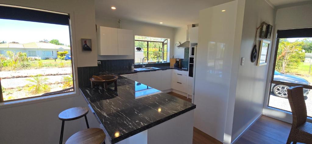 a kitchen with white cabinets and a black counter top at Bumble Bee Cottage in Kerikeri