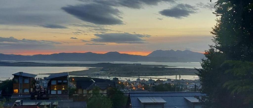 Casa Mirador Austral La familia entera en un solo lugar con una increíble vista y tranquilidad في أوشوايا: اطلالة على المدينة والمحيط وقت الغروب