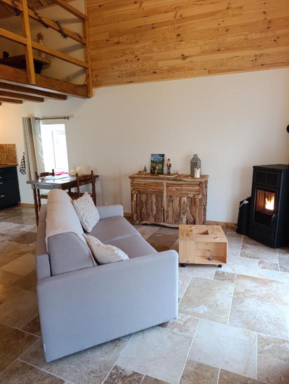 a living room with a couch and a wood stove at Le Grand Meix - La Petite Grange in Escles