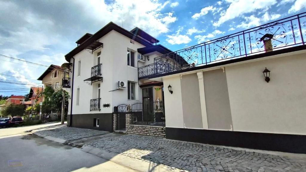 a white building with a balcony on top of it at Къща за гости Деметра in Velingrad