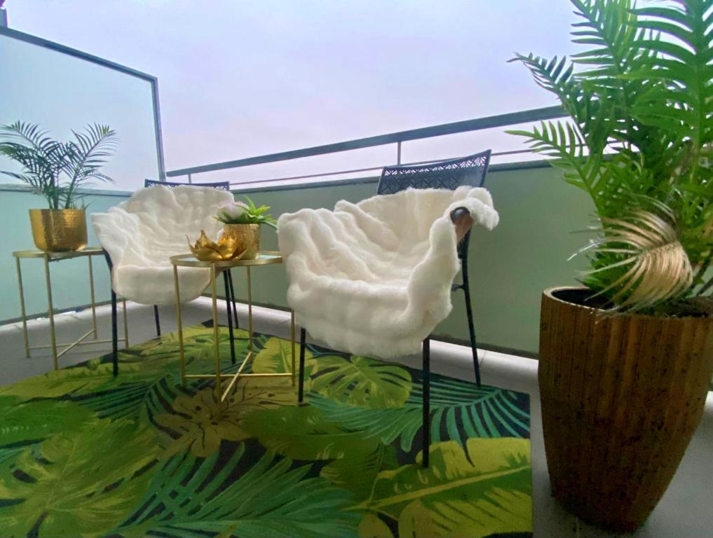 een kamer met twee witte stoelen, een tafel en planten bij APPOVEL- Balkonové Studio in Olomouc