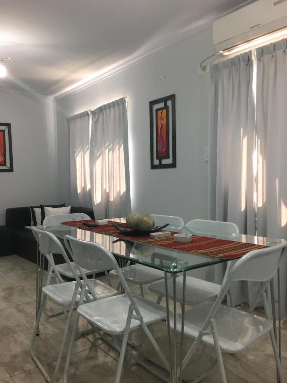 comedor con mesa de cristal y sillas blancas en Apartamento Los Abuelos Calle Peron en Colón