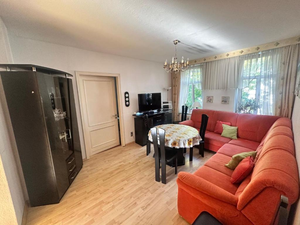 Fewo Warnemünde في روستوك: غرفة معيشة مع أريكة حمراء وطاولة