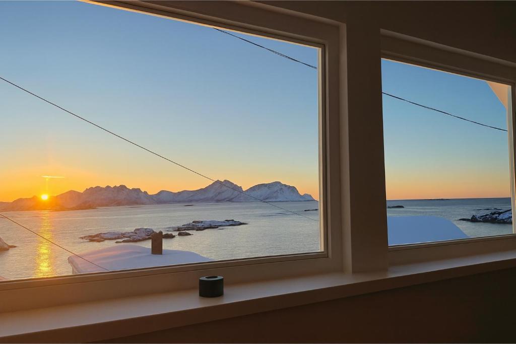 een raam met uitzicht op de oceaan en de bergen bij Arctic Nest in Nyksund