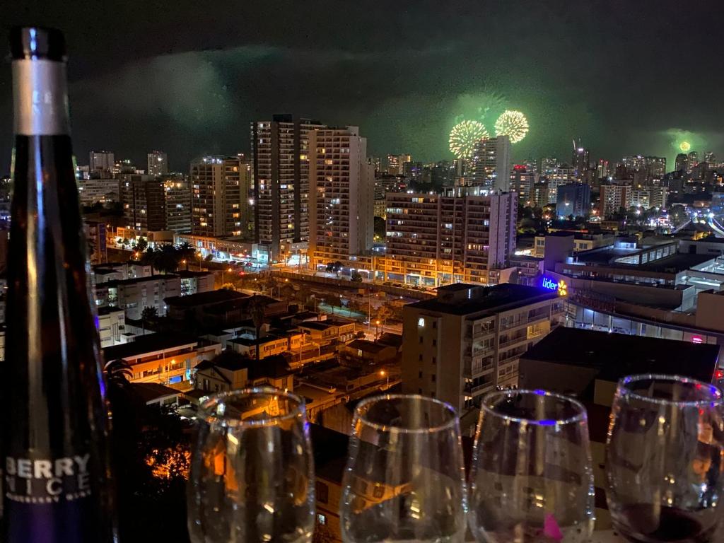 Un montón de copas de vino colocadas en una repisa con una ciudad. en Hermoso y moderno departamento, nuevo, a pasos de la Quinta Vergara, cercano a los mejores atractivos de viña del mar, con maravillosa vista, en Viña del Mar