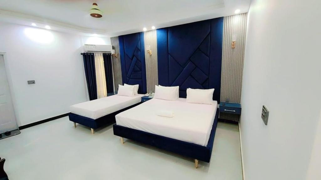 ein Schlafzimmer mit zwei Betten und einer blauen Wand in der Unterkunft Comfort Lodge in Karatschi