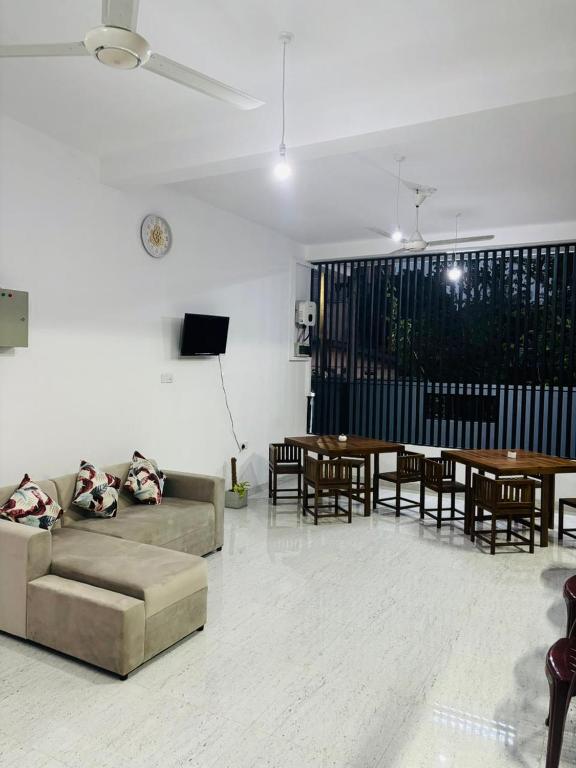 a living room with a couch and tables and a tv at Brampy Guest in Polonnaruwa