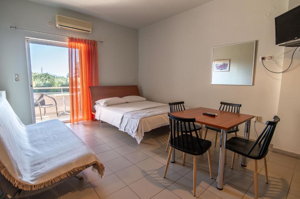 Voula Apartments في ميتيكاس: غرفة نوم بها سرير وطاولة وكراسي