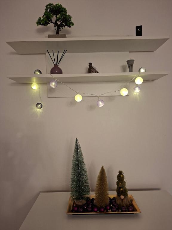 uno scaffale con alberi di Natale e luci su un tavolo di Studio apartman Franka a Vukovar