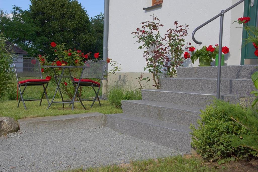 un conjunto de escaleras con 2 sillas y una mesa con flores en Panoramablick Höllbachtal, en Rettenbach