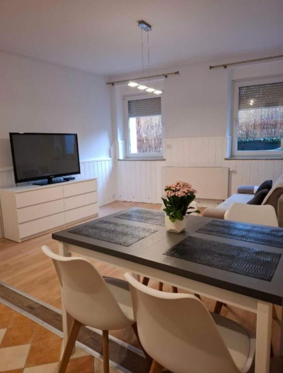 a living room with a table with chairs and a tv at Apartament Juliusz Slowacki in Szczawno-Zdrój