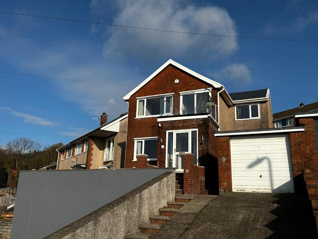 a brick house with a white garage at The Forager's Rest in Briton Ferry