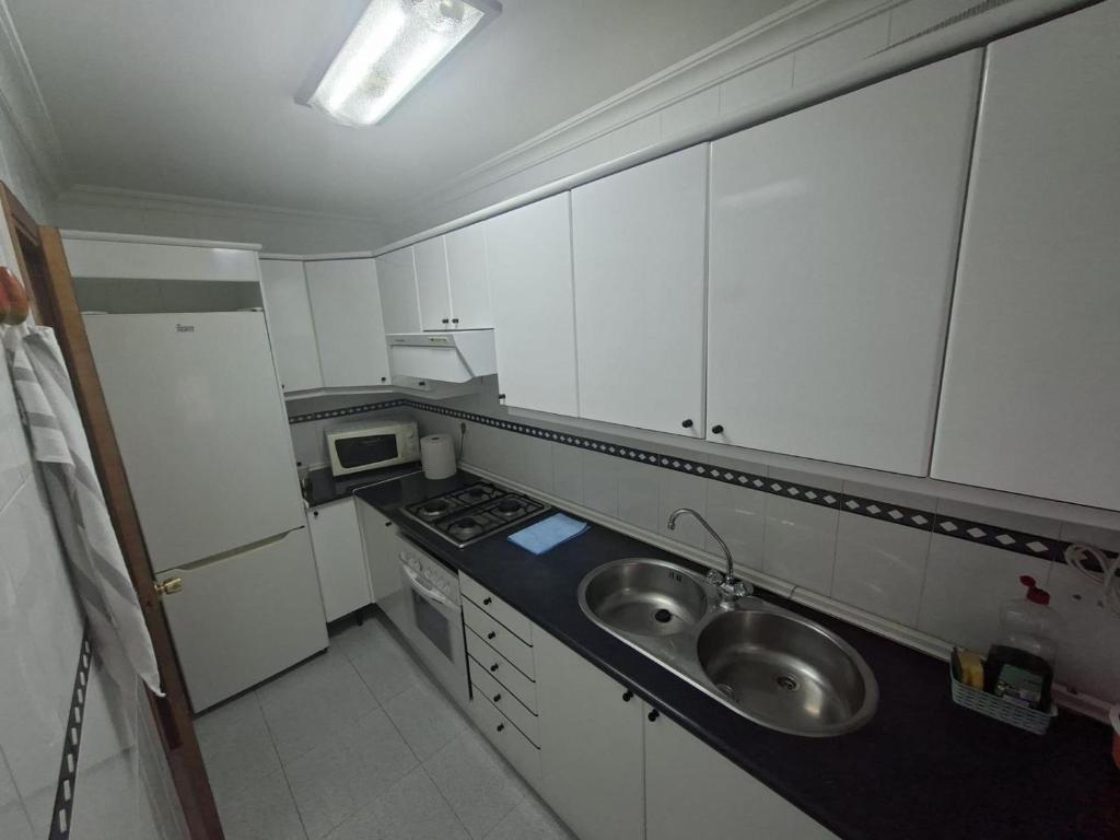 Una pequeña cocina con fregadero y estufa. en Confortable piso en Puertollano, en Puertollano