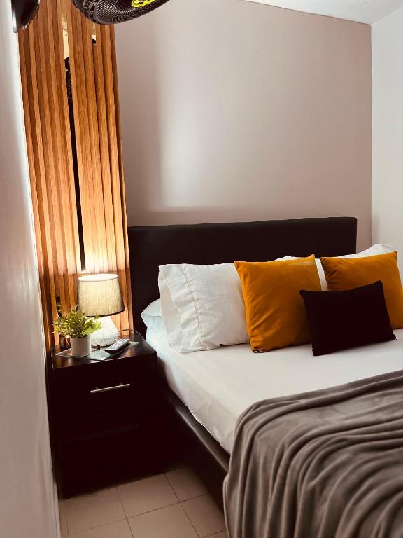 a bed with yellow and white pillows in a room at Apartaestudio Encanto Pacífico in Cali